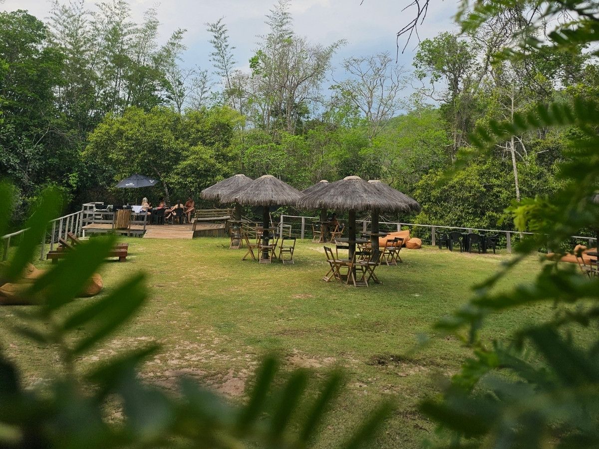 Área de descanso com ombrelones e gramado à beira da mata